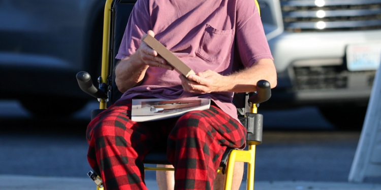 Andy Dick in a wheelchair, being pushed by a companion, on an afternoon outing in Los Angeles.