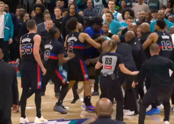 A basketball player with number 2 on his jersey fights another player, surrounded by players and security guards.