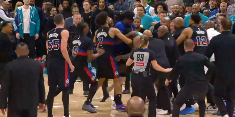 A basketball player with number 2 on his jersey fights another player, surrounded by players and security guards.