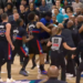 A basketball player with number 2 on his jersey fights another player, surrounded by players and security guards.