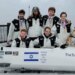 Members of Israel's Winter Olympics bobsleigh team, with Adam “AJ” Edelman (right), posing with their bobsled and a dog.