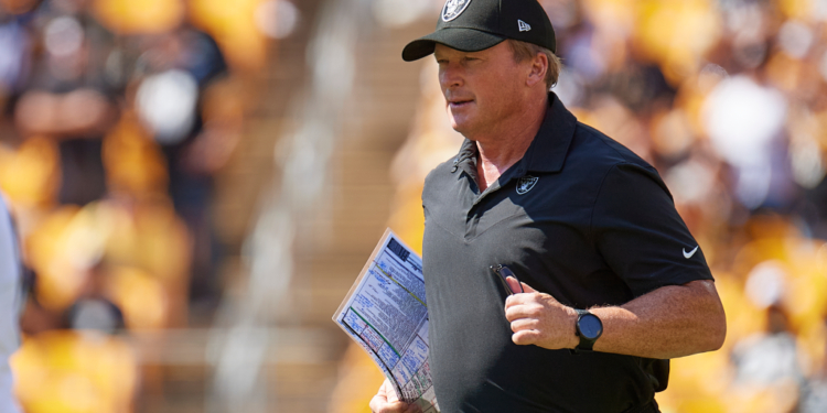 Las Vegas Raiders head coach Jon Gruden running on the field with a play sheet.