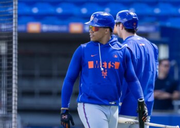 Juan Soto in a Mets helmet and blue Mets hoodie during spring training.