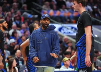 Injured Dallas Mavericks guard Kyrie Irving talks with forward Cooper Flagg during a timeout.