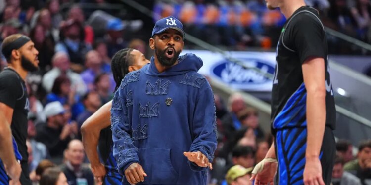 Injured Dallas Mavericks guard Kyrie Irving talks with forward Cooper Flagg during a timeout.