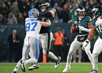 Detroit Lions defensive end Aidan Hutchinson being blocked by an Eagles offensive lineman while Jalen Hurts holds the football.