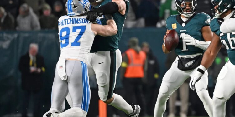 Detroit Lions defensive end Aidan Hutchinson being blocked by an Eagles offensive lineman while Jalen Hurts holds the football.