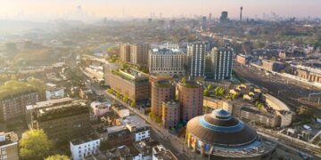 Illustration of the Camden Goods Yard development in London, featuring modern buildings, green roofs, and the Roundhouse.