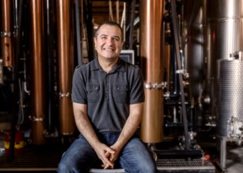 Melkon Khosrovian, owner of Greenbar Distillery, sitting in front of distillery equipment.