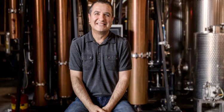 Melkon Khosrovian, owner of Greenbar Distillery, sitting in front of distillery equipment.