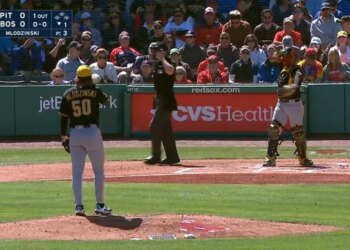 A baseball pitcher, catcher, and umpire on the field, with a scoreboard showing the Pirates and Red Sox are tied at 0.