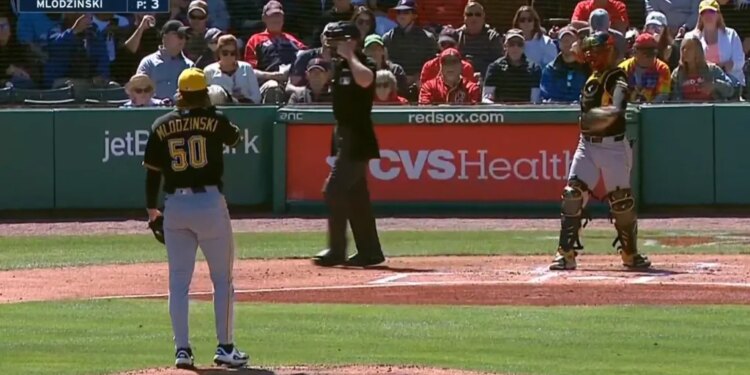 A baseball pitcher, catcher, and umpire on the field, with a scoreboard showing the Pirates and Red Sox are tied at 0.