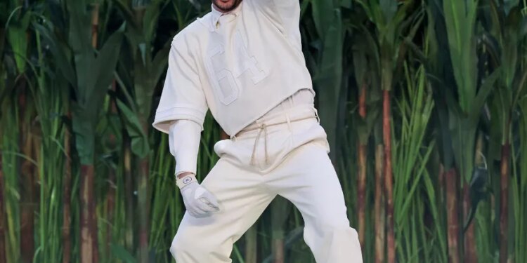 Bad Bunny performing during the Super Bowl halftime show, wearing a white outfit and pointing up.