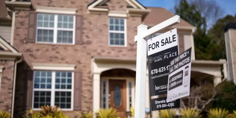 "For Sale" sign in front of a brick house.