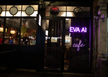 Outside view of a wine bar where you can see people through the window. In neon purple lights is the word EVA AI cafe.
