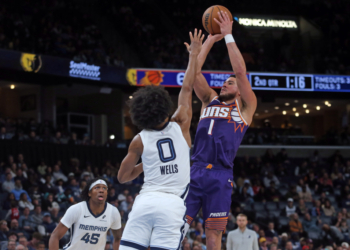 Phoenix Suns guard Devin Booker (1) shoots as Memphis Grizzlies forward Jaylen Wells (0) defends him.