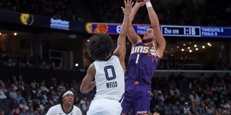 Phoenix Suns guard Devin Booker (1) shoots as Memphis Grizzlies forward Jaylen Wells (0) defends him.