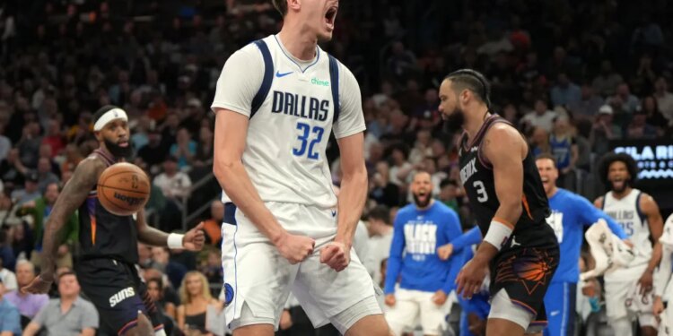 Dallas Mavericks player Davis Bertans shouts in celebration, fists clenched, after making a basket, with a Phoenix Suns player behind him.
