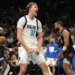 Dallas Mavericks player Davis Bertans shouts in celebration, fists clenched, after making a basket, with a Phoenix Suns player behind him.