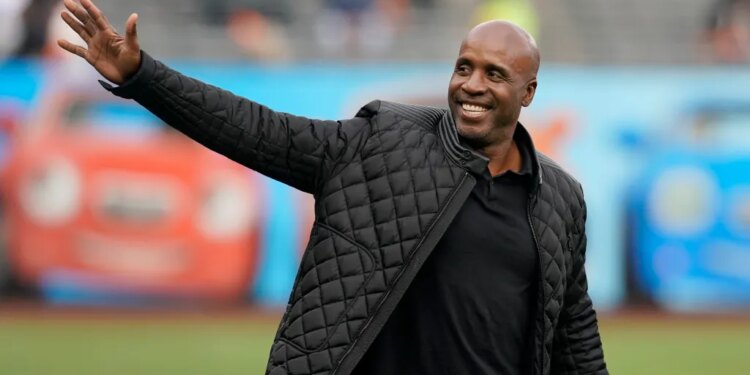 Barry Bonds in a black jacket waving with a smile.