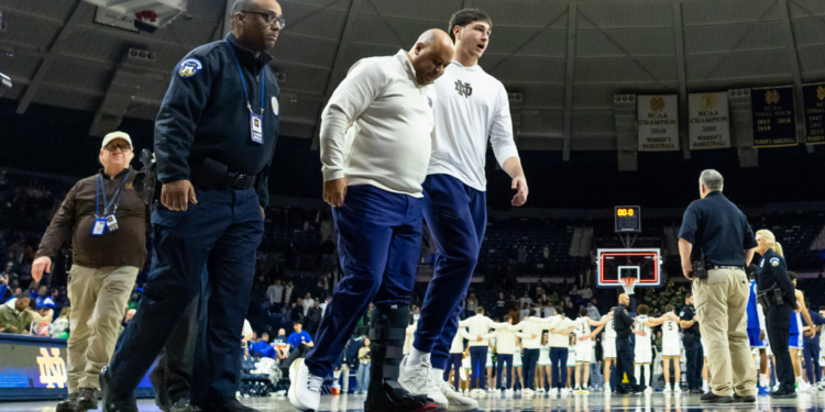 Notre Dame head coach Micah Shrewsberry is helped off the court while wearing a boot.