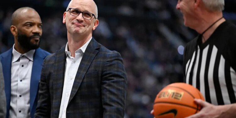 UConn head coach Dan Hurley smiles at official Brian O'Connell during an NCAA college basketball game.