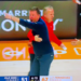 A basketball coach with his arm around another coach points and yells at a referee.