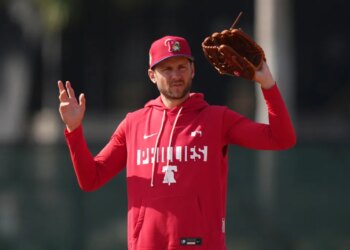 Trea Turner of the Philadelphia Phillies in a red Phillies hoodie and hat holding a baseball glove.