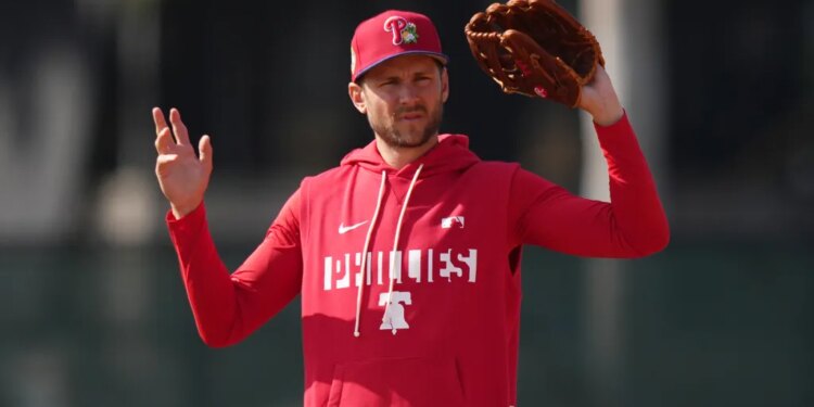 Trea Turner of the Philadelphia Phillies in a red Phillies hoodie and hat holding a baseball glove.