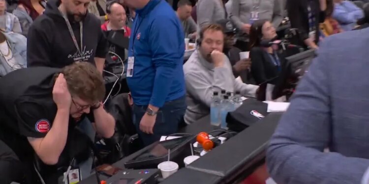 People covering their ears during a Pistons-Cavaliers game due to a loud horn malfunction.