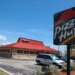 A Pizza Hut restaurant with a red roof and a large sign in the foreground, located in Florida, USA.