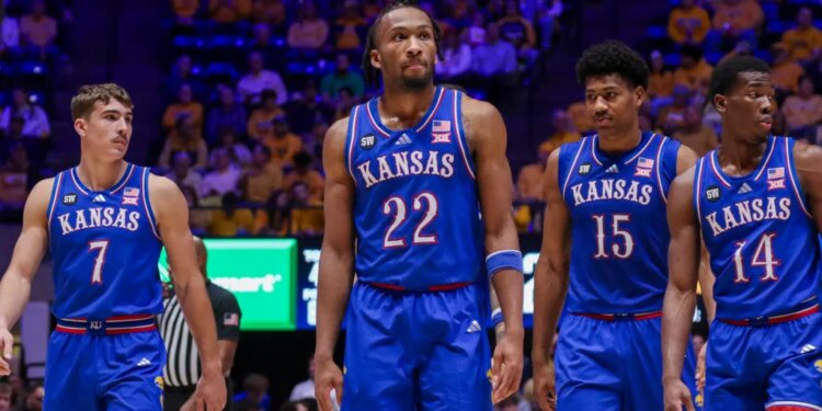 Four Kansas basketball players in blue uniforms standing on the court.