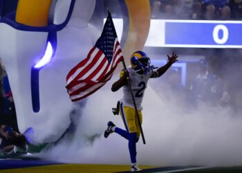 Robert Woods running onto the field carrying an American flag.