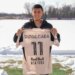 Red Bull New York player Ruvalcaba holds up his number 11 jersey on a snowy field.
