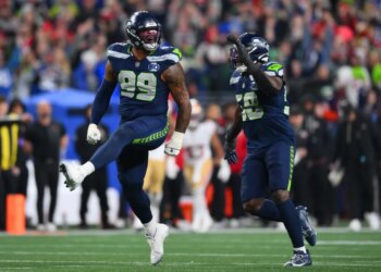 Seattle Seahawks players Leonard Williams (99) and Derick Hall (58) celebrating after sacking the San Francisco 49ers quarterback.