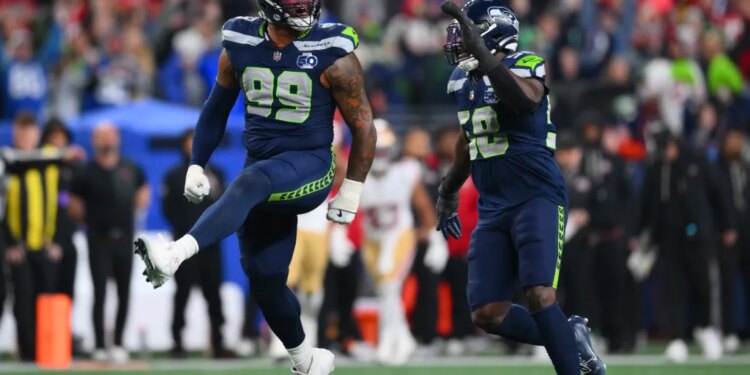Seattle Seahawks players Leonard Williams (99) and Derick Hall (58) celebrating after sacking the San Francisco 49ers quarterback.