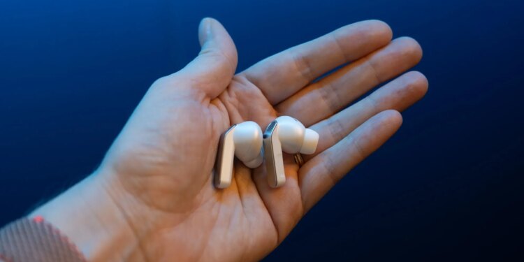 The Samsung Galaxy Buds 4 Pro in the palm of a hand with a blue background.