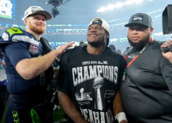 Sam Darnold with his arm around Kenneth Walker III, who is wearing a Super Bowl LX Champions shirt, celebrating their victory.