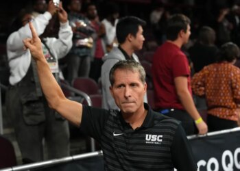 Southern California Trojans head coach Eric Musselman holds up a "Fight On" sign after a victory.