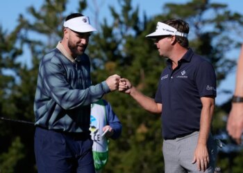 Travis Kelce and Keith Mitchell fist-bumping on a golf course.