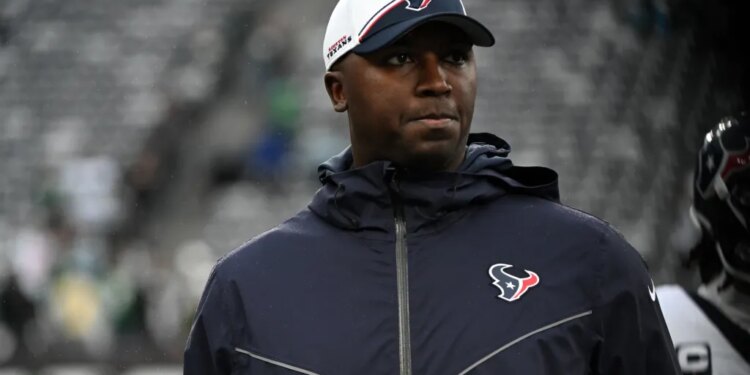 A man wearing a white Houston Texans baseball cap and dark blue jacket looks to the right.
