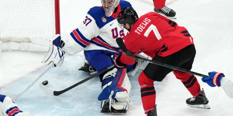 Connor Hellebuyck (37) uses his stick to block a shot by Canada's Devon Toews (7) during the third period of the men's ice hockey gold medal game at the 2026 Winter Olympics in Milan, Italy, Sunday, Feb. 22, 2026.