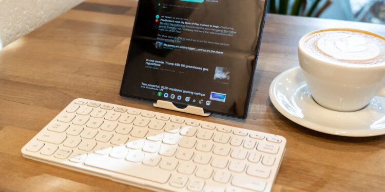 Folding phone propped up on a table with a travel keyboard.