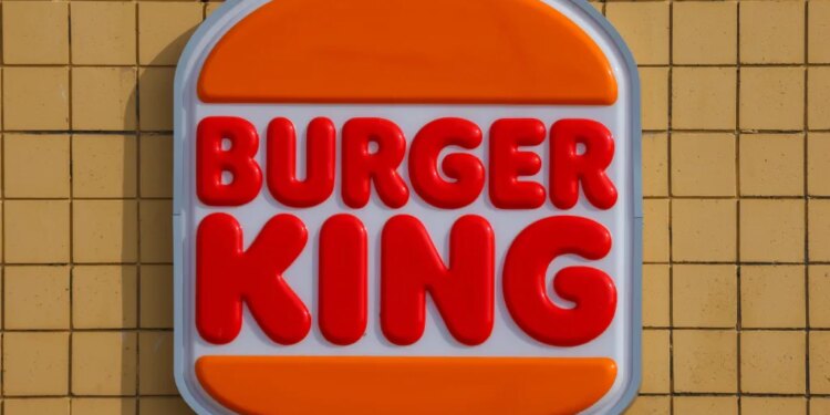 Burger King sign featuring red bold letters for "BURGER KING" between two orange bun shapes.