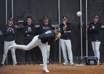 New York Yankees pitcher Carlos Lagrange #84 throwing during spring training with four coaches observing in the background.