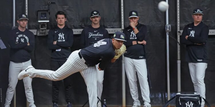 New York Yankees pitcher Carlos Lagrange #84 throwing during spring training with four coaches observing in the background.