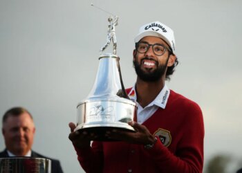 Akshay Bhatia smiles as he holds up the Arnold Palmer Invitational golf trophy.