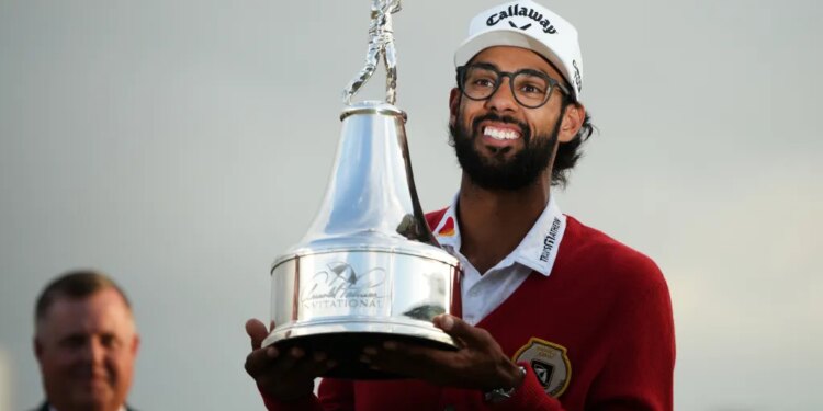 Akshay Bhatia smiles as he holds up the Arnold Palmer Invitational golf trophy.