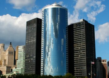 The curved glass skyscraper of 17 State Street, Manhattan, New York, USA, reflecting the sky.
