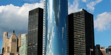 The curved glass skyscraper of 17 State Street, Manhattan, New York, USA, reflecting the sky.